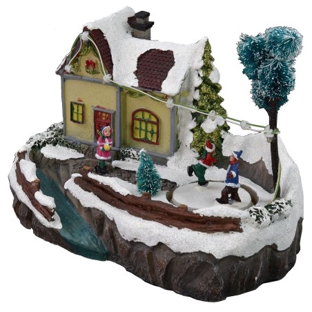 Escenario navideño con casa y pista de patinaje en funcionamiento.