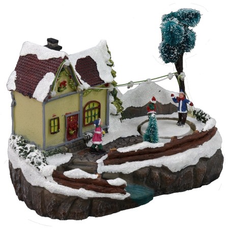 Escenario navideño con casa y pista de patinaje en funcionamiento.