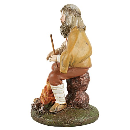 Shepherd with staff sitting in front of the fire in painted resin.