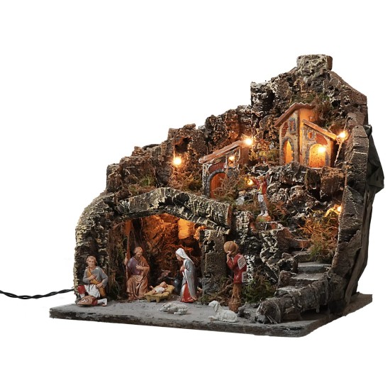 Illuminated nativity scene with village on mountain complete with statues