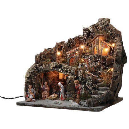 Pesebre iluminado con pueblo en montaña completo de estatuas.