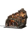 Illuminated nativity scene with village on mountain complete with statues