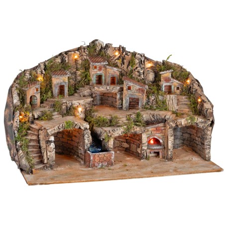 Illuminated nativity scene with caves, little houses, stream, and oven
