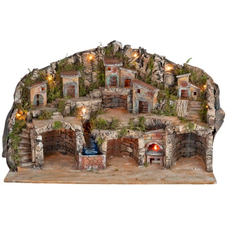 Illuminated nativity scene with caves, little houses, stream, and oven