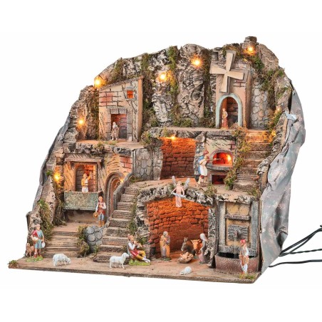 Illuminated nativity scene with statues, fountain, fire, and windmill