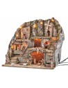 Illuminated nativity scene with statues, fountain, fire, and