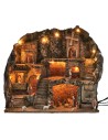 Illuminated nativity scene with statues, fountain, fire, and windmill