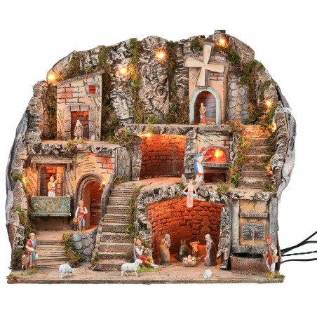 Illuminated nativity scene with statues, fountain, fire, and