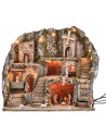 Illuminated nativity scene with statues, fountain, fire, and windmill