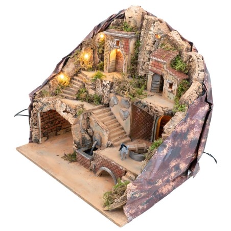 Illuminated nativity scene with fountain and donkey at moving millstone