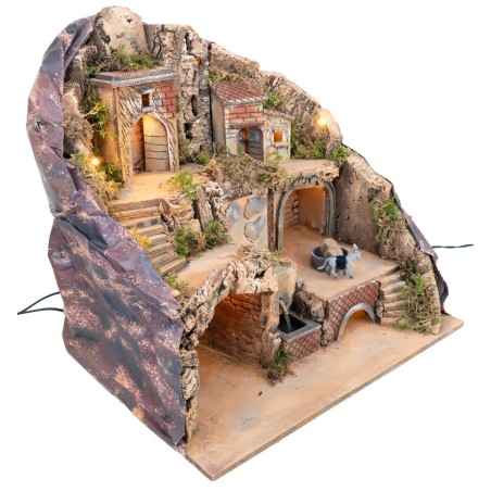 Illuminated nativity scene with fountain and moving donkey at
