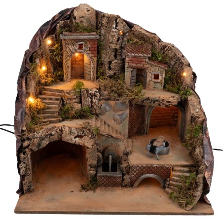 Illuminated nativity scene with fountain and donkey at moving millstone