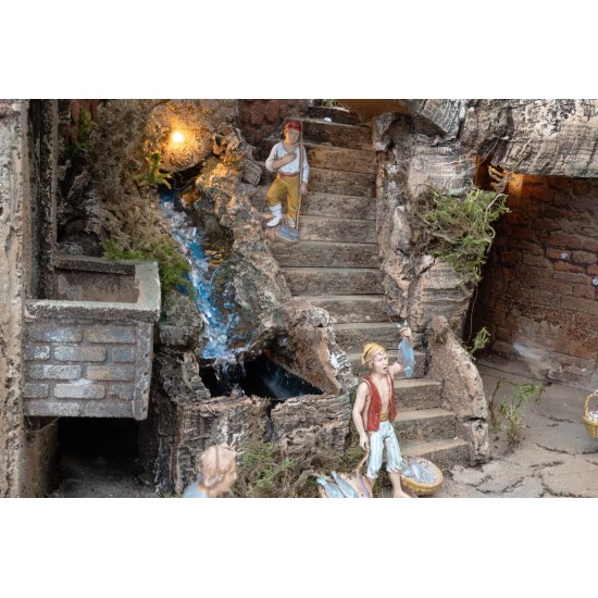 Illuminated nativity scene with statues, stream, oven, and windmill